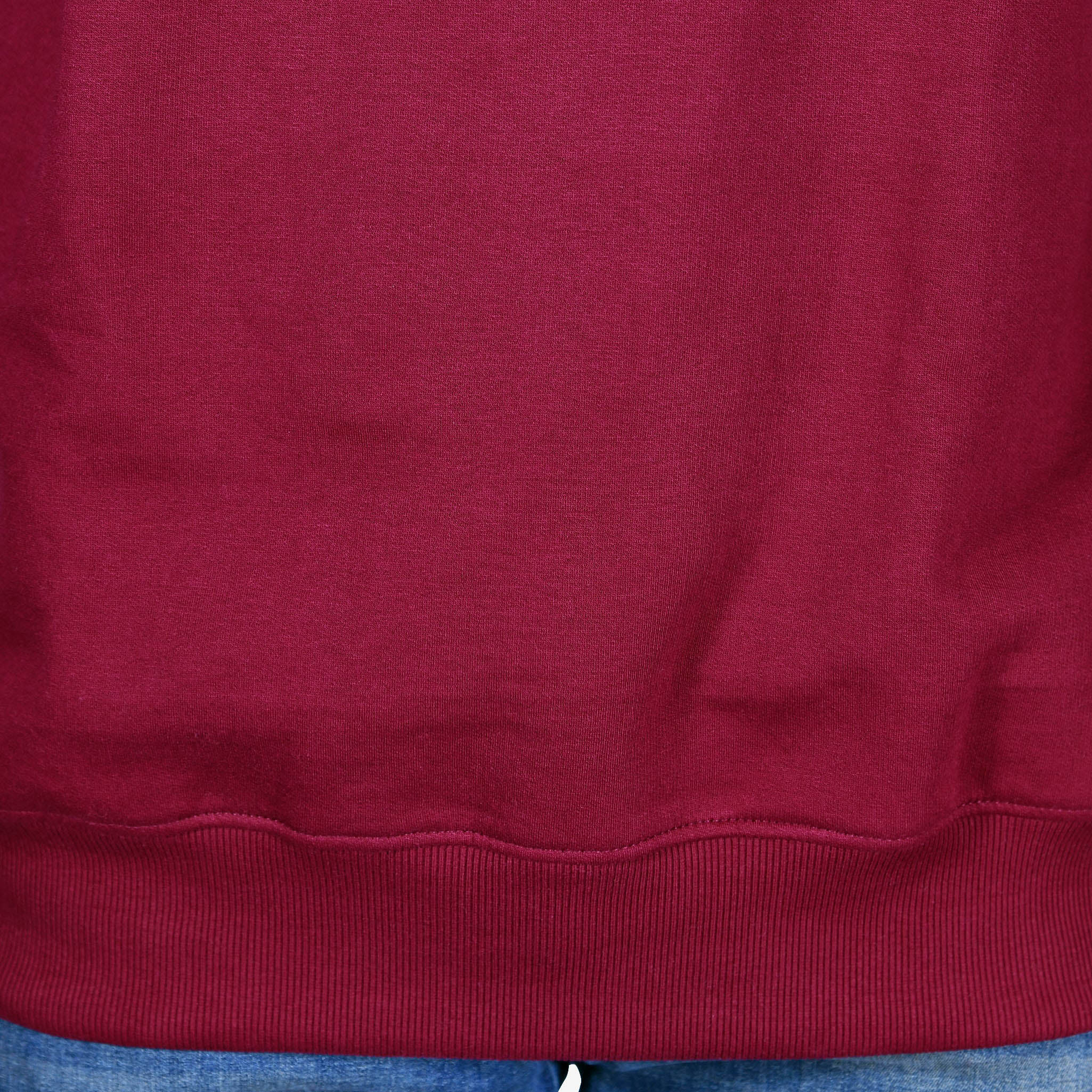 A person modeling an oversized maroon sweatshirt with a relaxed fit